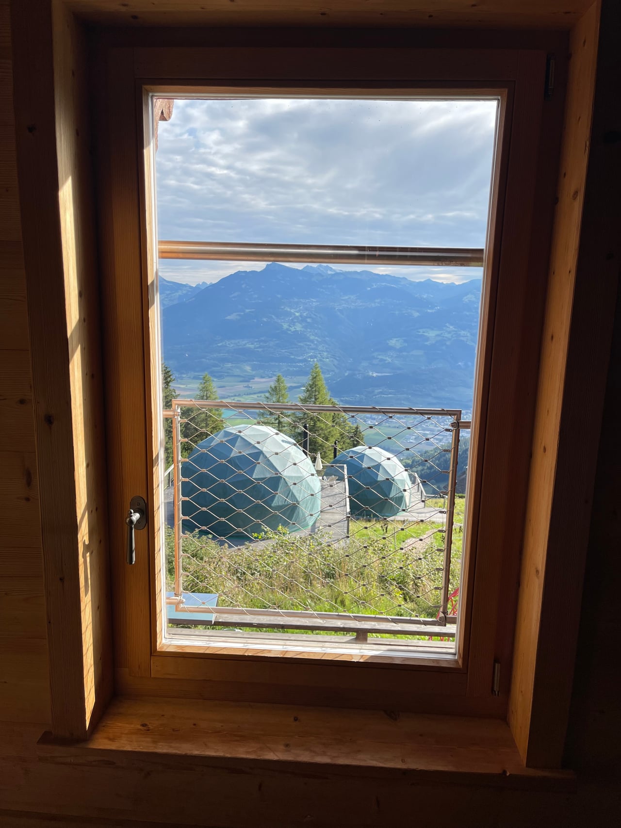 The mountains and geodesic pods seen through a chalet window above the breakfast table
