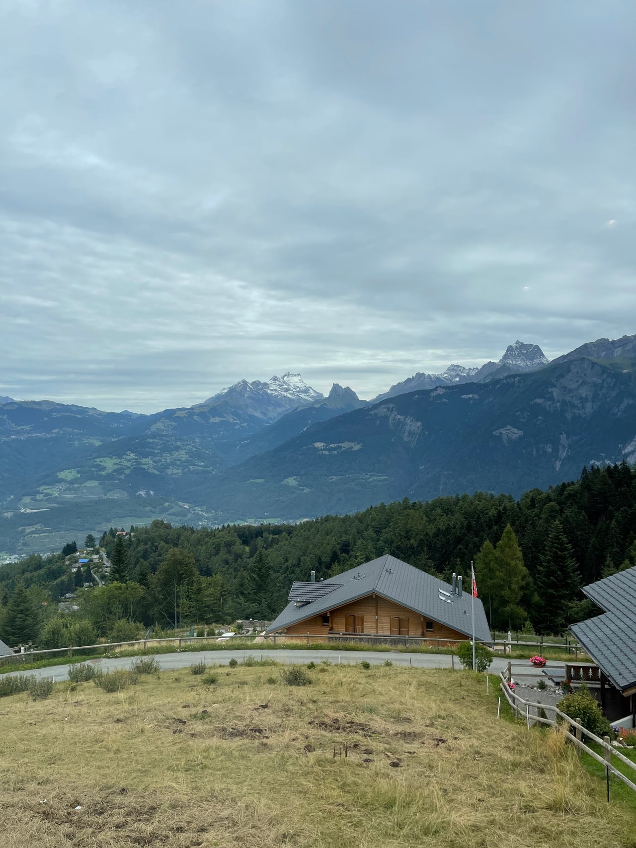 A timber Whitepod chalet on the hillside with the Dents-du-Midi rising beyond
