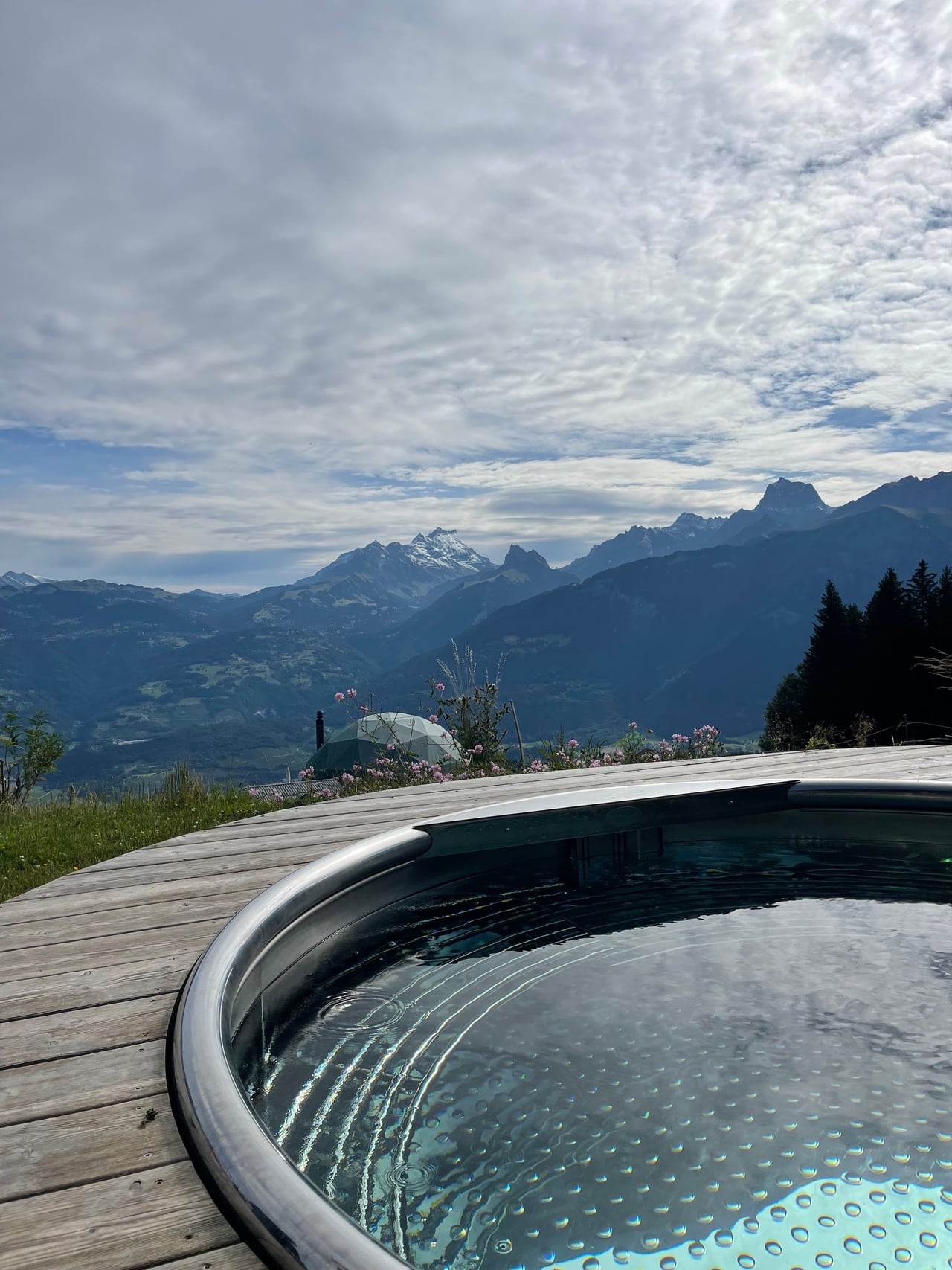 A Nordic hot tub on the deck at Whitepod Original with a panorama of the Swiss Alps
