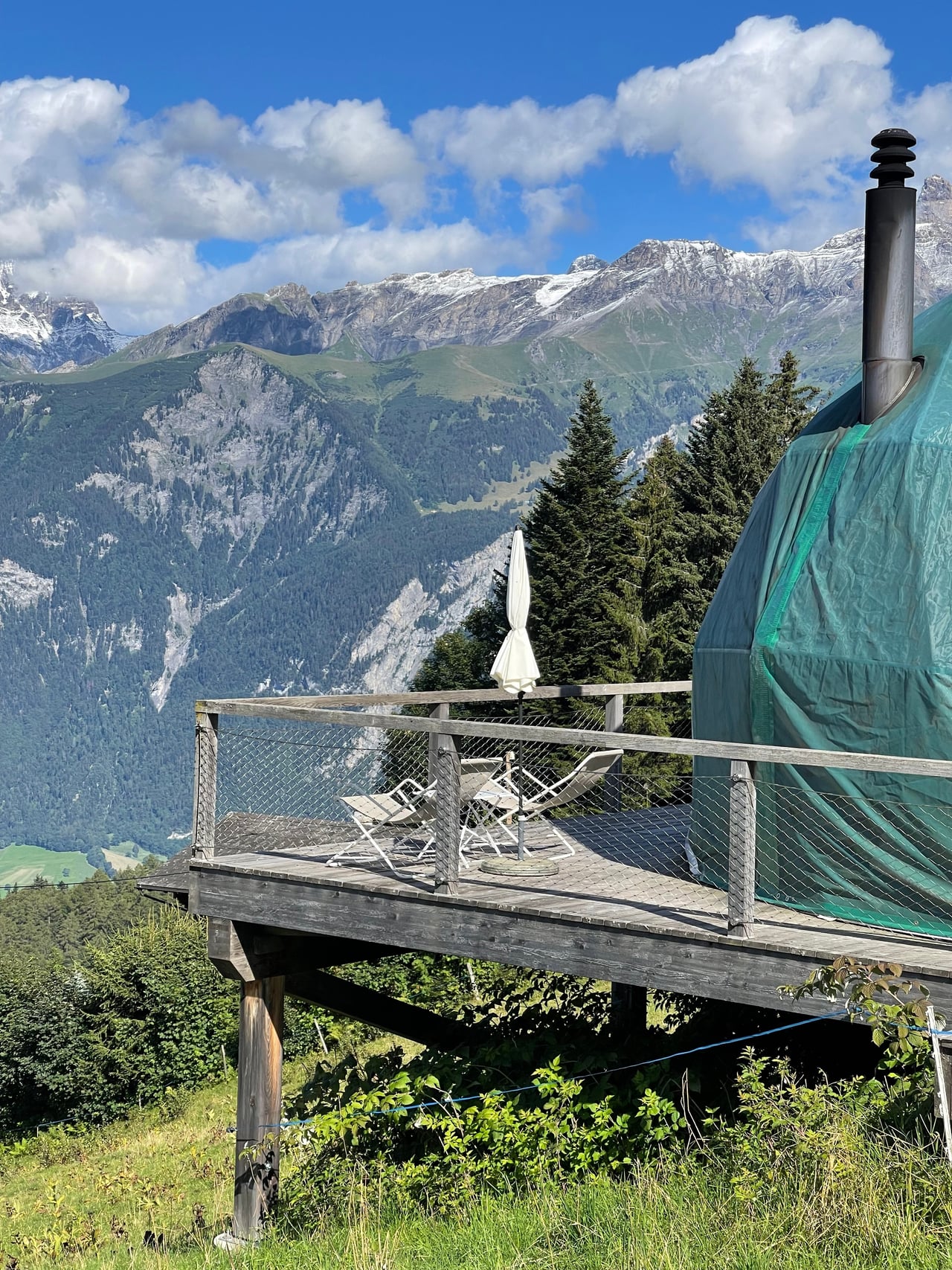 A private pod terrace with loungers and a parasol overlooking the Swiss Alps