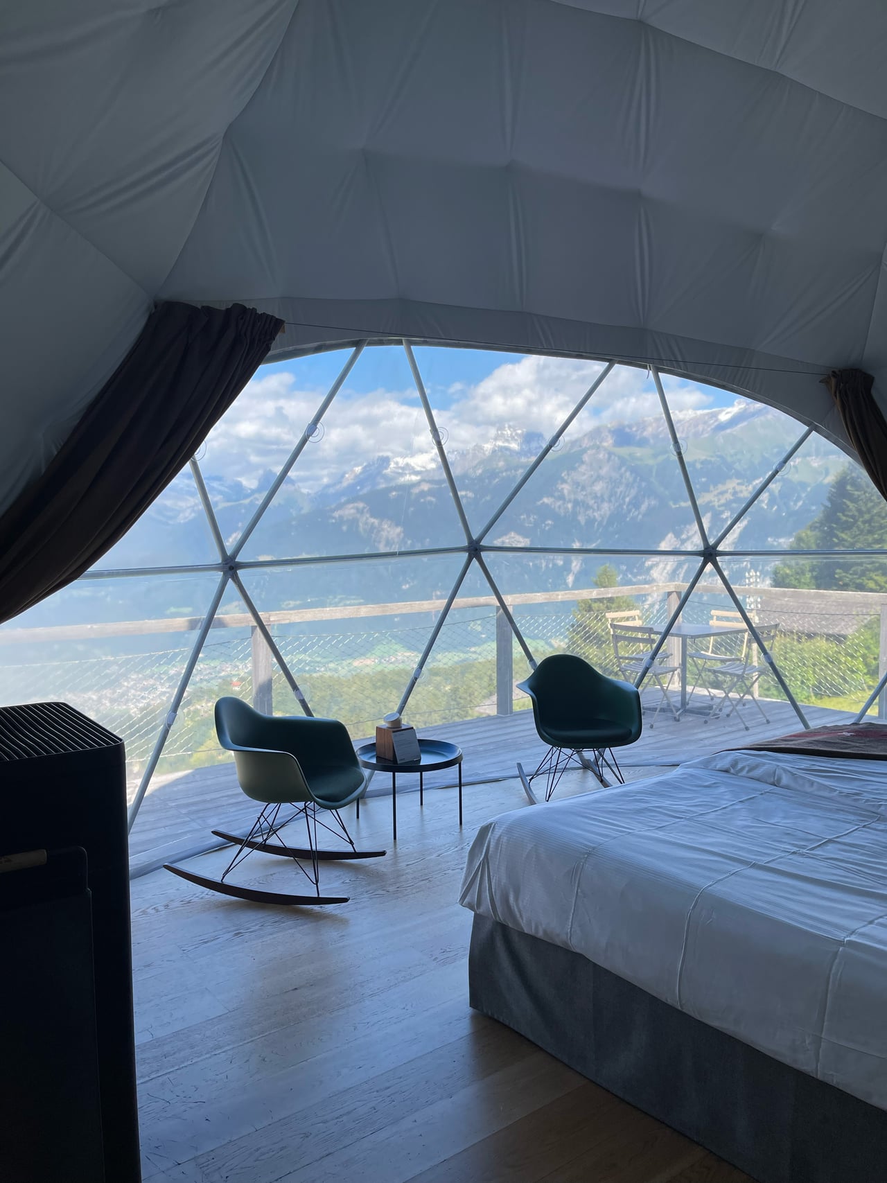 The interior of a Whitepod pod looking across the valley through the triangulated dome windows